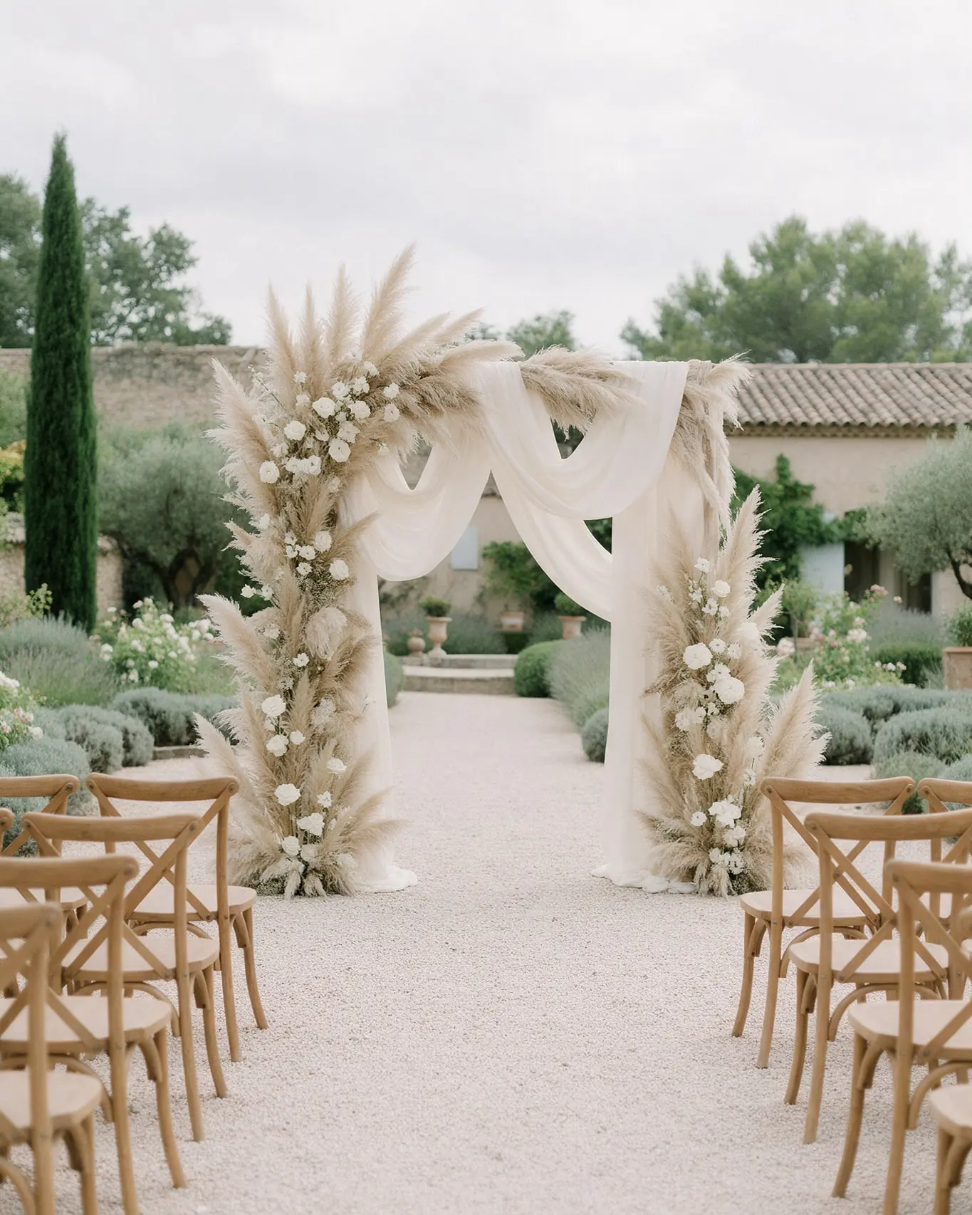Arche de cérémonie laïque en voilage ivoire, herbes de la pampa et roses blanches, chaises en bois