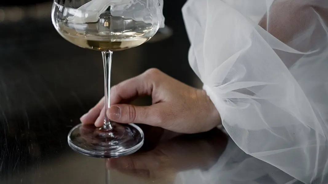 Coupe de champagne tenue par la mariée, voile en tulle en transparence