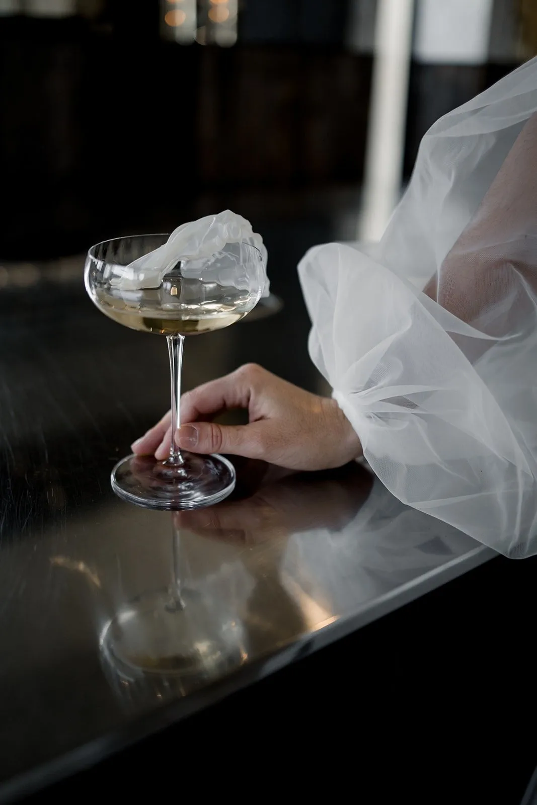 Coupe de champagne tenue par la mariée, voile en tulle en transparence