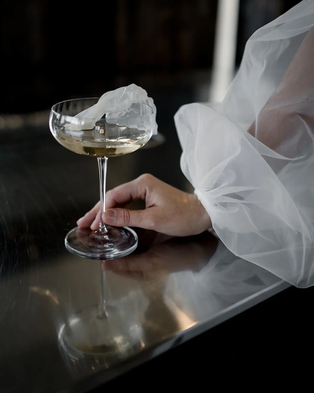 Coupe de champagne tenue par la mariée, voile en tulle en transparence